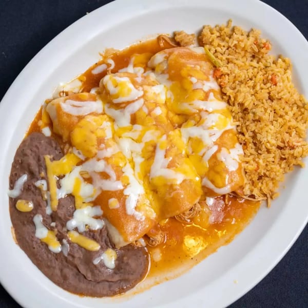 A white plate with three cheesy enchiladas, refried beans, and Spanish rice.
