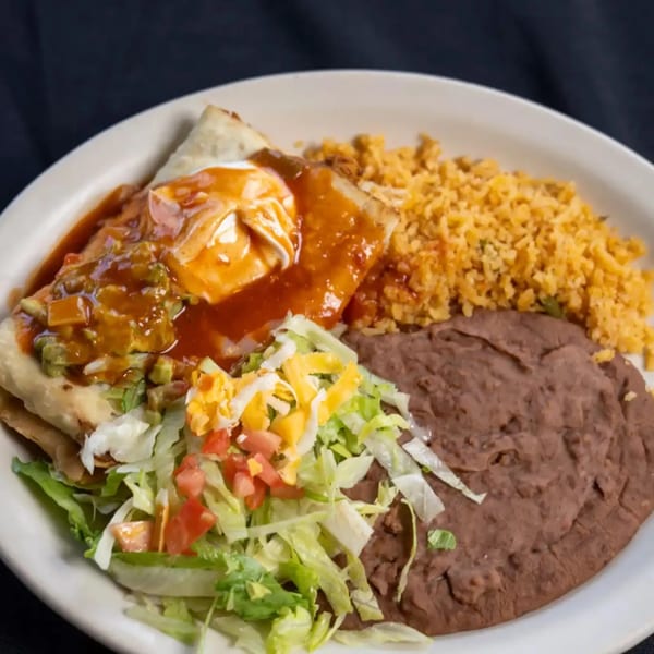 A plate of Mexican food with a burrito, rice, refried beans, and a side salad.